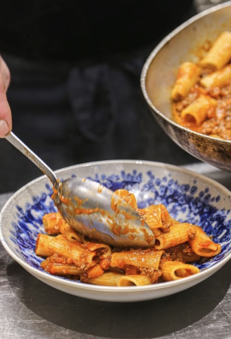 Rigatoni à la bolognaise servis dans une assiette bleue